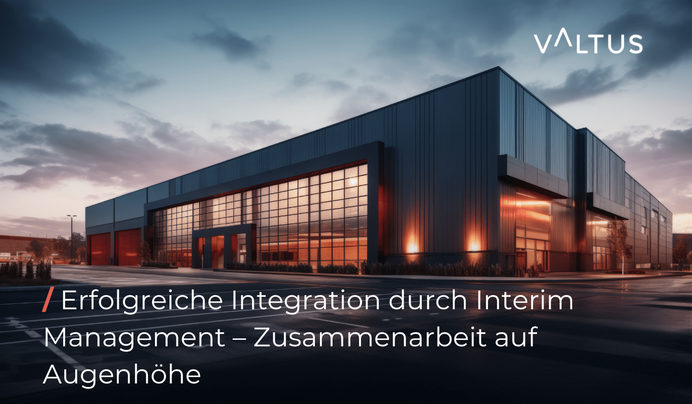 Moderne Industriehalle bei Sonnenuntergang, Glasfassade mit warmem Innenlicht, Symbolbild für erfolgreiche Integration eines Produktionsstandorts durch Interim Management – Valtus-Logo oben rechts